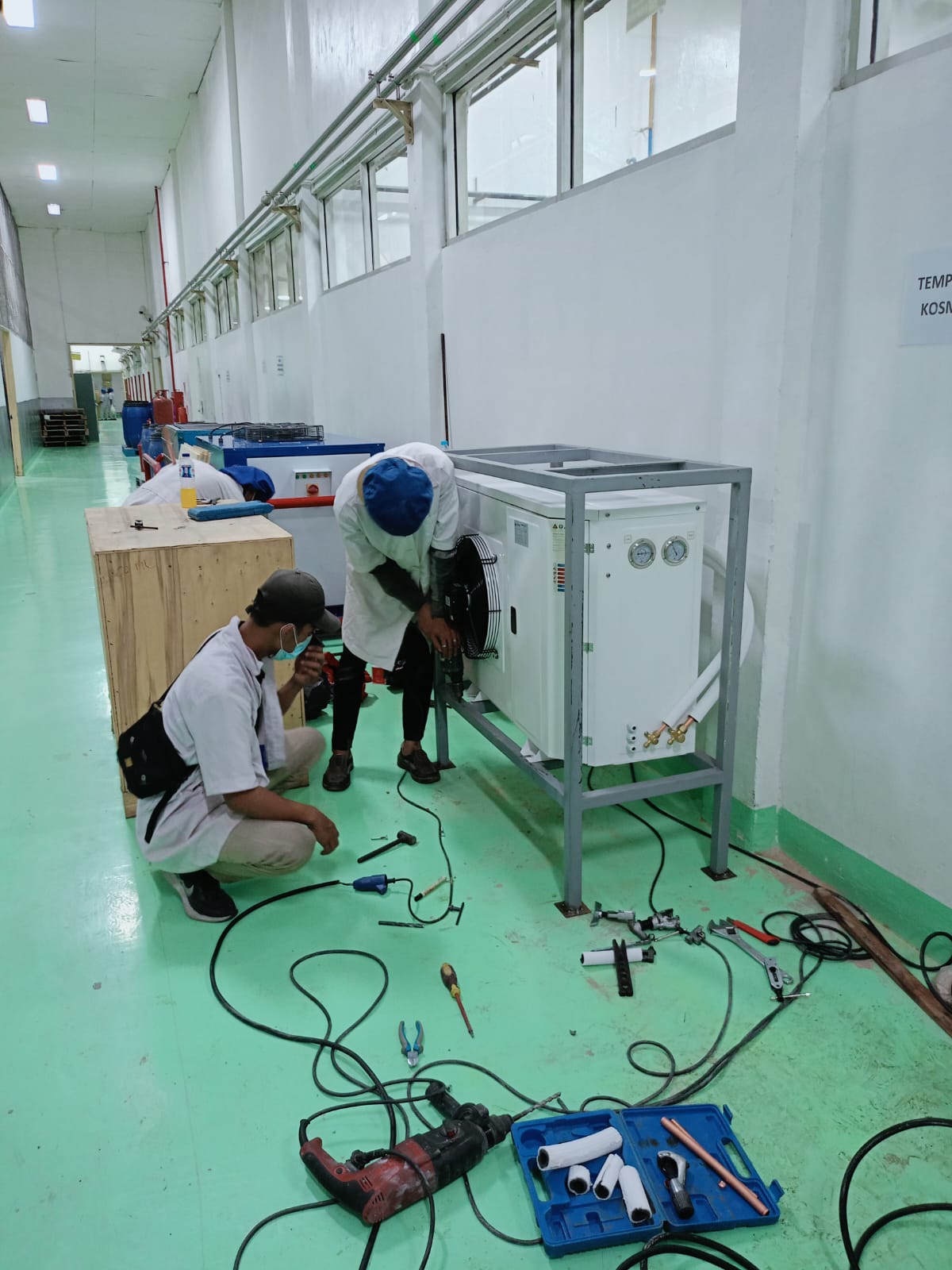 Teknisi sedang merakit dan melakukan pengecekan pada condensing unit pendingin industri